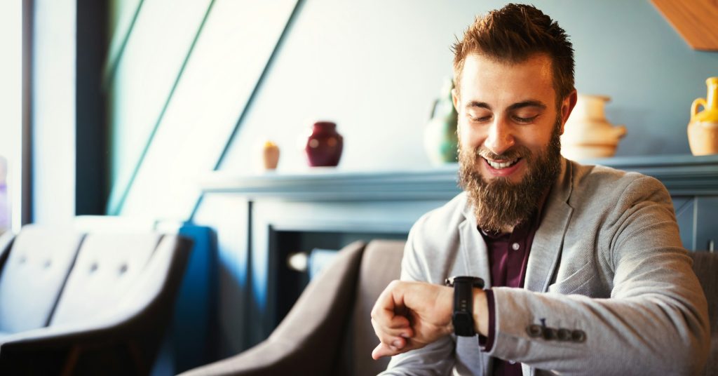 Business and time management concept. Happy business man looking at wrist watch